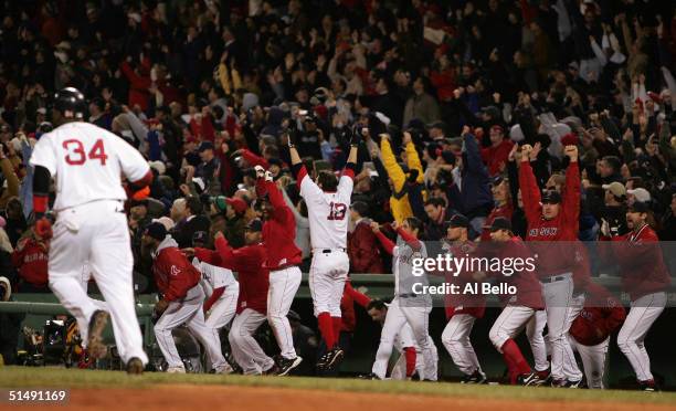 David Ortiz of the Boston Red Sox runs to first base as the dugout celebrates his game winning two-run home run in the twelth inning to defeat the...