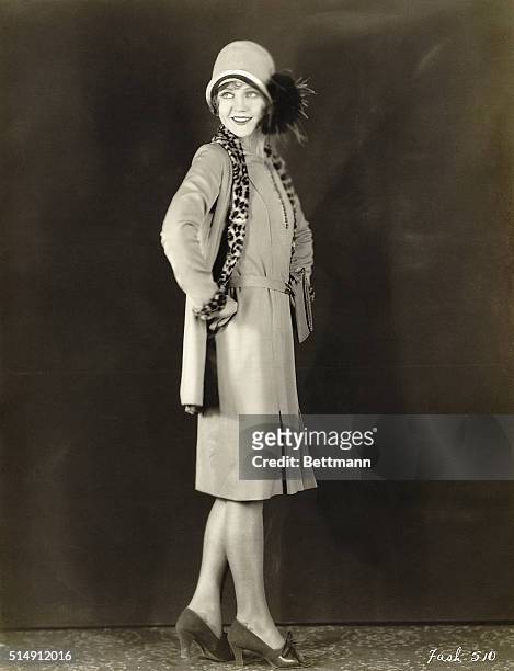 Picture shows Nancy Carrol modeling a dress suit. The jacket is lined with a leopard fur pattern and a close fitted hat with fur accent finishes the...