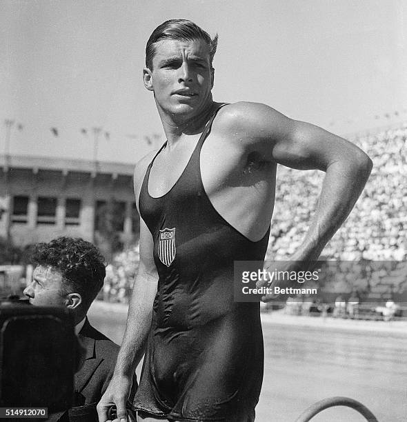 After winning gold in the 400-meter freestyle event at the Los Angeles Olympic Games, Buster Crabbe of the United States loosens up his tank suit....