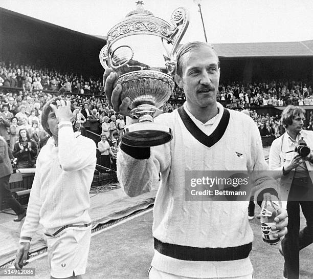 Wimbledon, England- Stan Smith holds the winner's cup after 5 set triumph in Men's Singles final here July 9th. The dejected loser, Romania's Ilie...
