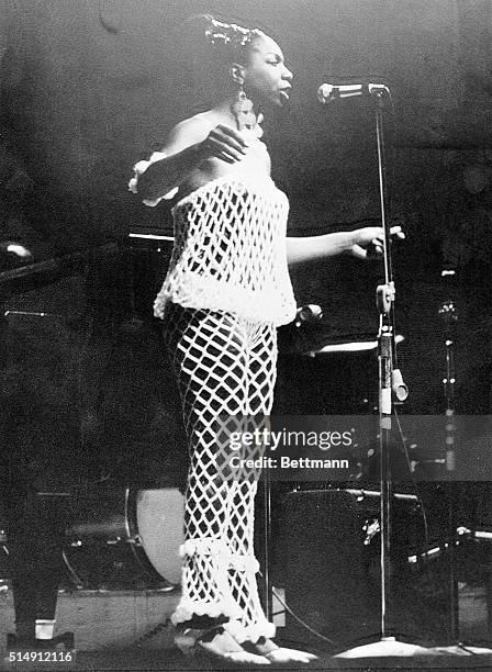 Newport, RI- Nina Simone wears a revealing net costume at Newport Jazz Festival. She is shown singing on stage.