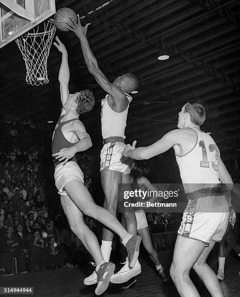 Melbourne, Australia- BIG BILL SINKS ONE. America's Big Bill Russell reaches high above the head of Russia's A. Lauritenas to score a rebound shot...