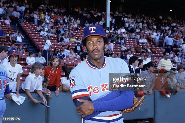 Texas Rangers' pitcher Fergie Jenkins stands in front a stadium of fans with his arms folded across his chest.