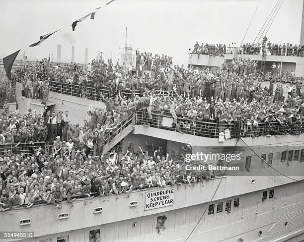 Making her fist trip here since V-E Day, the giant British Liner, Queen Mary sails past the New York skyline on her way to the pier to bring home...