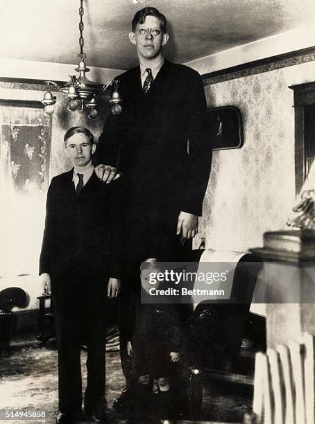 Robert Wadlow, 8 feet 5 3/4 inches tall at age 18, standing besides his brothers Eugene age 14, and Harold age 3 1/2 at their home in Alton, Illinois.