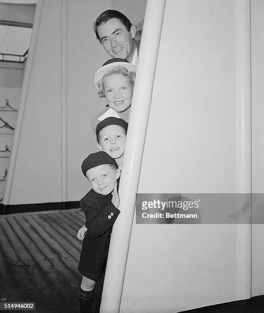 Movie actor Gregory Peck with his wife and children peek at the cameraman aboard the SS Queen Elizabeth at they return from England. From top to...