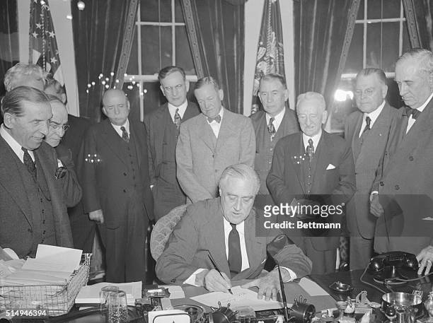 Determined President Franklin D. Roosevelt, Commander in Chief of the nation's armed forces signs the Resolution declaring that a State of War exists...