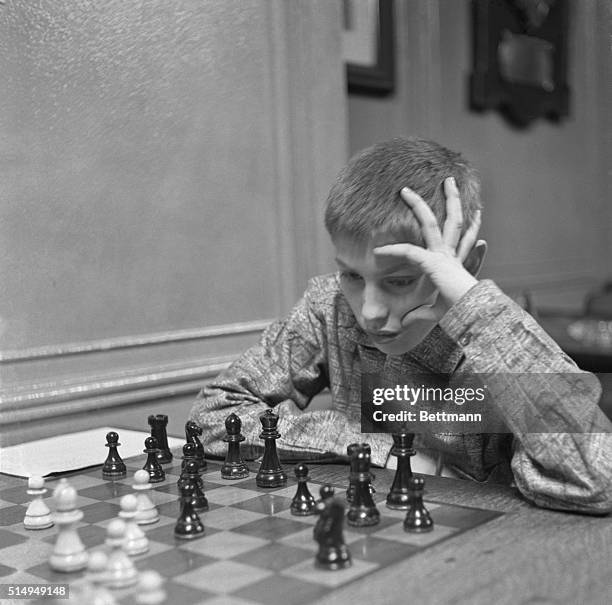 Restless hands play about the head of thirteen year old Bobby Fischer of Brooklyn as the youngest member of the Manhattan Chess Club takes part in a...