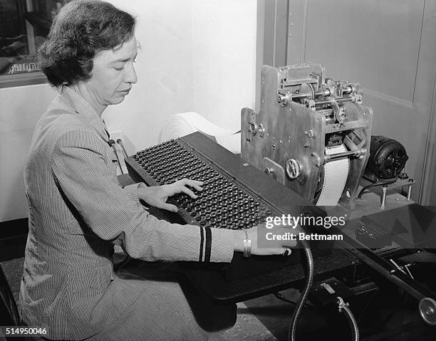 Lieutenant Grace Hopper codes problems onto punch tape for feeding into a new calculating machine invented by Commander Howard H. Aiken, USNR. The...