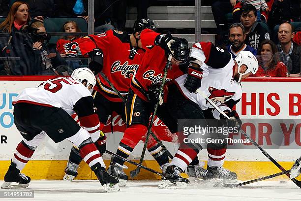 Kenny Agostino of the Calgary Flames skates against Nicklas Grossman of the Arizona Coyotes during an NHL game at Scotiabank Saddledome on March 11,...