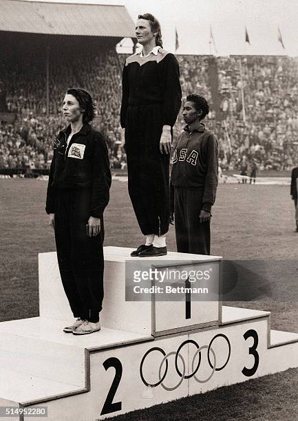 London, England- Mrs. Fanny Blankers-Koen, Holland's "flying housewife," and the runners-up, stand to attention on the victory rostrum at Wembley...
