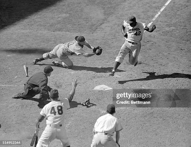 Catcher Toby Atwell scrambles for Dodger second baseman Jackie Robinson, who crosses home plate to score the winning run in the last half of the...