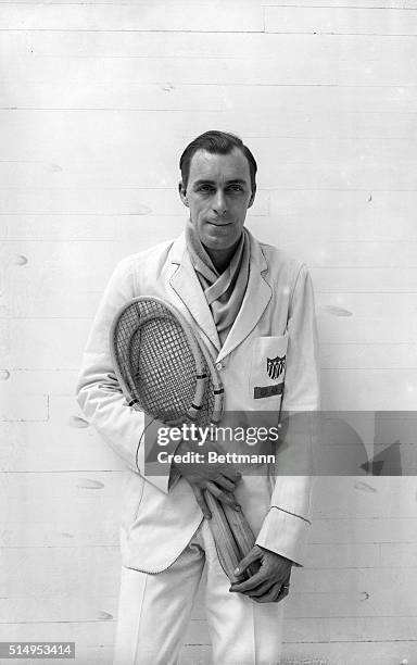 Picture shows tennis professional, Bill Tilden, posing in a tennis jacket and holden two rackets.