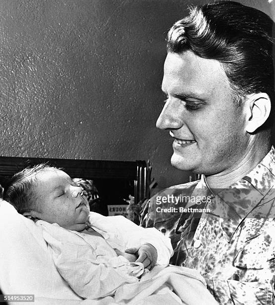 Billy Graham, evangelist who has drawn some of the biggest crowds in the history of his calling, proudly holds his son, Billy, Jr., born in...