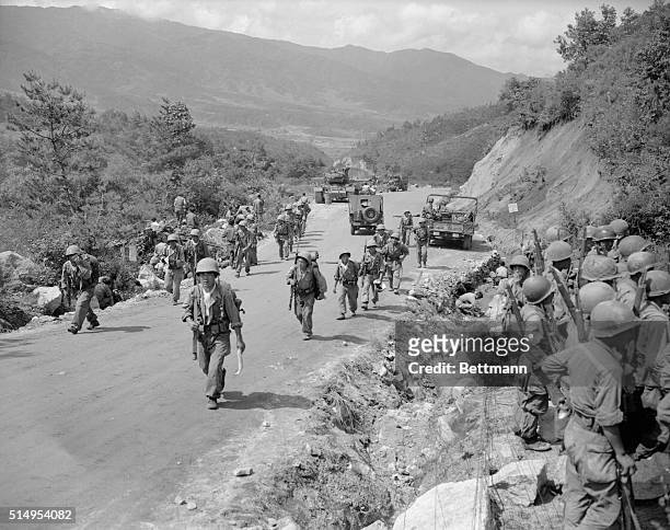 As soldiers at right are briefed, other ROK Troopers move up the road to forward positions for counterattack against Chinese Communists who launched...