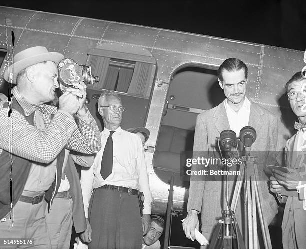 Howard Hughes, millionaire flier and movie producer, is pictured smiling as he speaks over the air, and is photographed at La Guardia Field on...