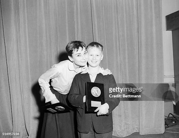 Actress Audrey Hepburn gives fellow Thespian Brandon De Wilde a congratulatory hug, as he holds a copy of Look magazine's 13th annual Film...