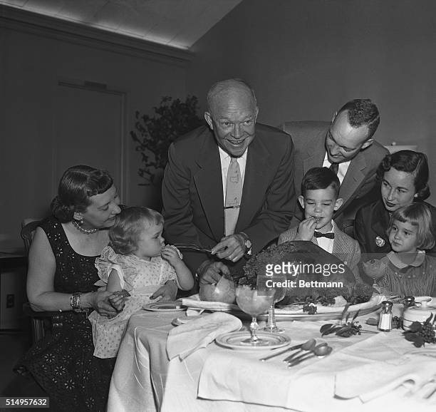 Augusta, GA- The Eisenhower family gathers around the President, as he prepares to carve the Thanksgiving Day turkey at "Mamie's cabin," the vacation...