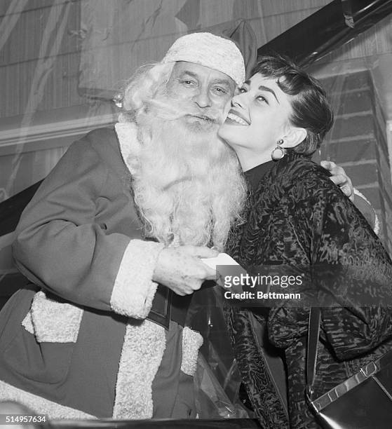 New York, NY- Audrey Hepburn, recently named the top movie star of 1953 by "Film Daily," gets a kiss from Santa Claus during ceremonies at the "Heart...