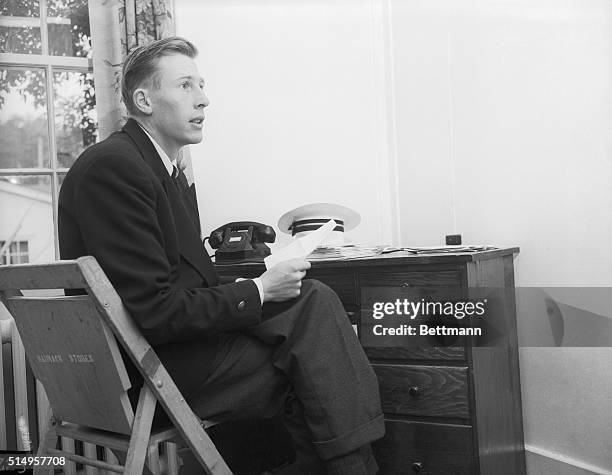 Britain's Roger Bannister, first to break the four-minute mile barrier, reads a telegram from an English fan in his hotel room at Vancouver. He faces...