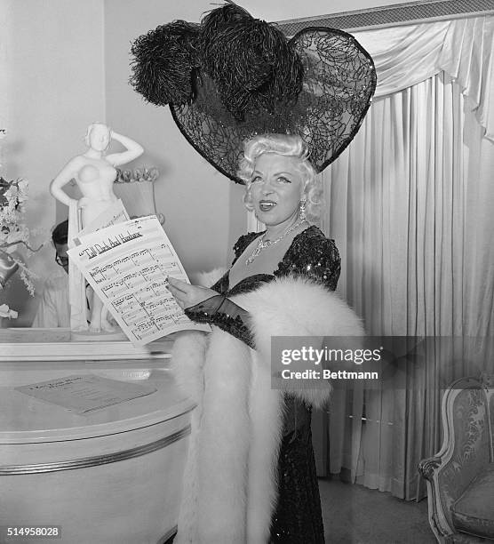 Mae West, well-known to the boys, who looks younger with their hats on, for her famous remark, "Come up 'n see me sometime," returns to show business...
