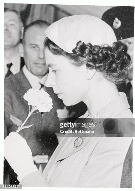Britain's graceful young Queen Elizabeth II holds a newly blossomed carnation and samples its fragrance in Windsor Great Park. Her Majesty attended...