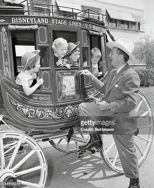The creator of Mickey Mouse, Pluto, and Donald Duck, Walt Disney, with gun in hand, halts a stagecoach bulging with smiling youngsters in the...