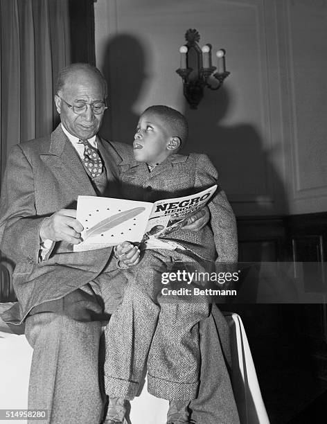 Year-old Matt Henson co-discoverer, with Admiral Peary, of the North Pole, reads the first issue of "negroe heroes" to six-year-old Neil David, son...