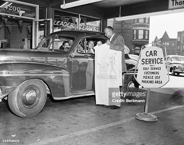 Jesse Owens, track star and now co-owner of cleaning plant in Chicago, serving customer. Customers are served by driving their autos through in front...
