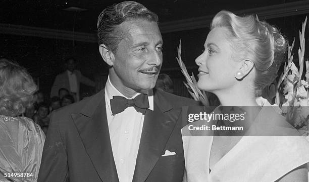 Actress Grace Kelly and Oleg Cassini, who have become one of Hollywood's most romantically linked couples, chat in the lobby of a theater during the...