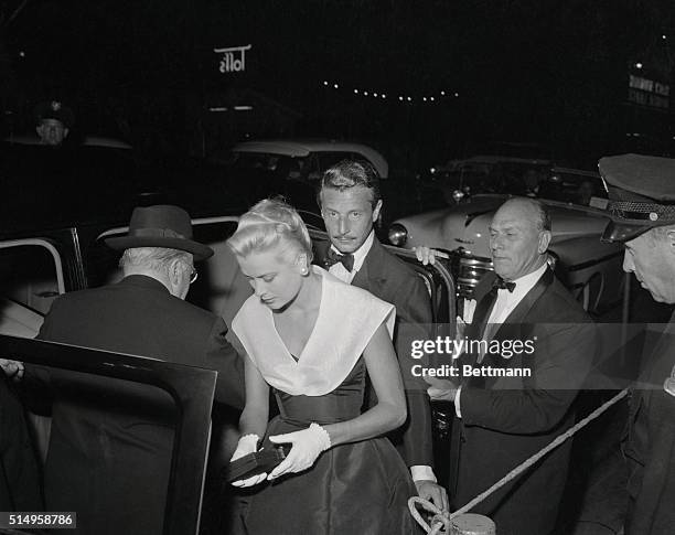 Actress Grace Kelly and Oleg Cassini, who have become one of Hollywood's most romantically linked couples, arrive at the theater before the premiere...