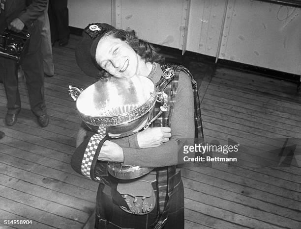 Arriving aboard the S.S. Queen Elizabeth in New York is Babe Didrikson Zaharias who holds the trophy she won by capturing the British Women's Amateur...