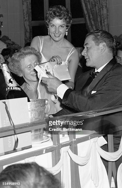 Hollywood actor Errol Flynn wins a small bottle to perfume in the lottery at Deauville's casino. He was among the notables attending a benefit ball...