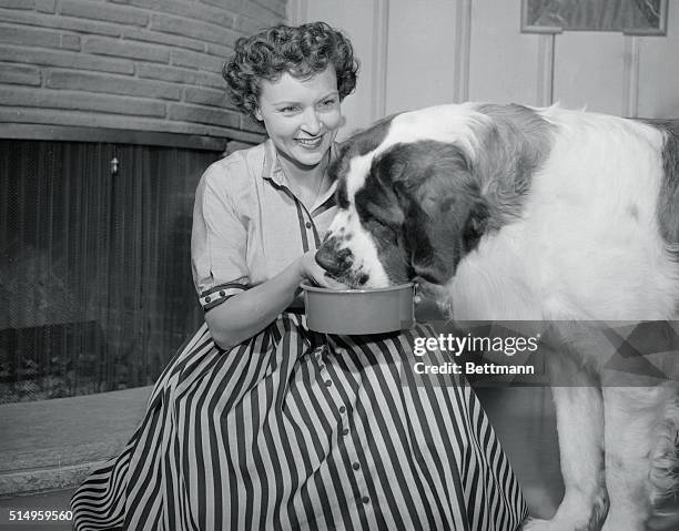 Betty White, star of DuMont's Life with Elizabeth show, has just about enough time to feed her huge St. Bernard, Stormy, before dashing off to the...