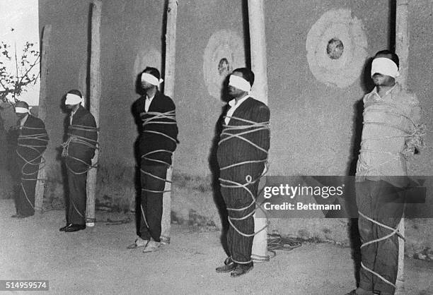 Blindfolded and bound to stakes, five of ten alleged Communist spies await death before a firing squad in the Ghasr Army Barracks in Tehran. Nine...