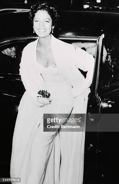 Singer Dorothy Dandridge flashes a beautiful smiles as she arrives at the Rivoli Theater at the premier of the CinemaScope Technicolor movie version...