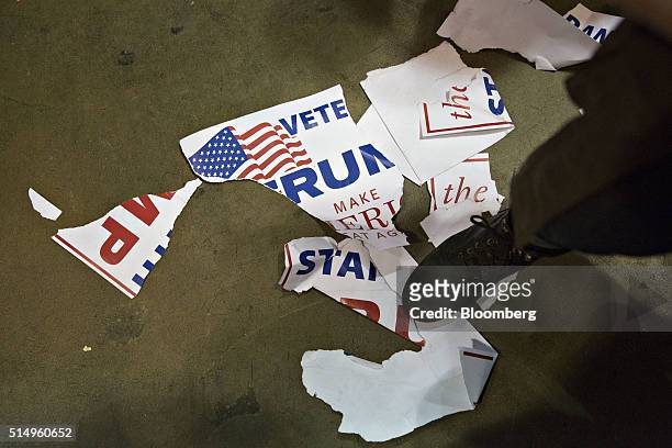 Man stands on a torn campaign sign during a canceled campaign event with Donald Trump, president and chief executive of Trump Organization Inc. And...