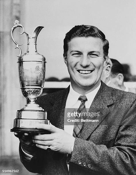 Smiling Australian golfer Peter Thomson proudly holds his trophy after winning the British Open golf championship with a 72 hole score of 281, to...