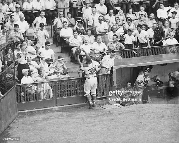 Dodger catcher Roy Campanella drags down a foul pop-up by Milwaukee's Joe Adcock in the ninth inning of the opener at Ebbets Field and Braves player...