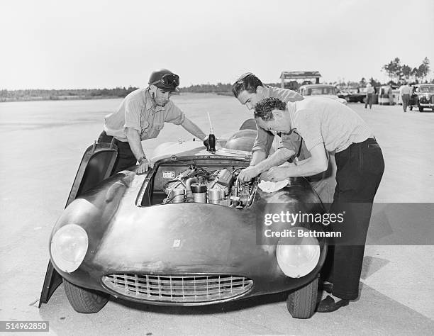 Spain's Marquis de Portago concentrates on the engine of his sleek Ferrari as mechanics Giannino Parravicini and Enzo Monari, both of Italy, make...
