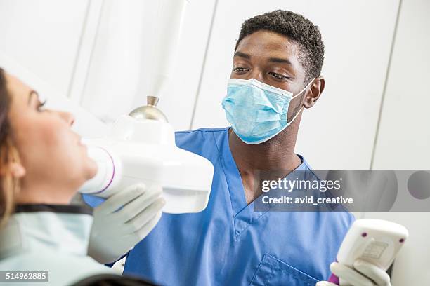 young black dentist x-rays patient teeth - tandartsassistent stockfoto's en -beelden