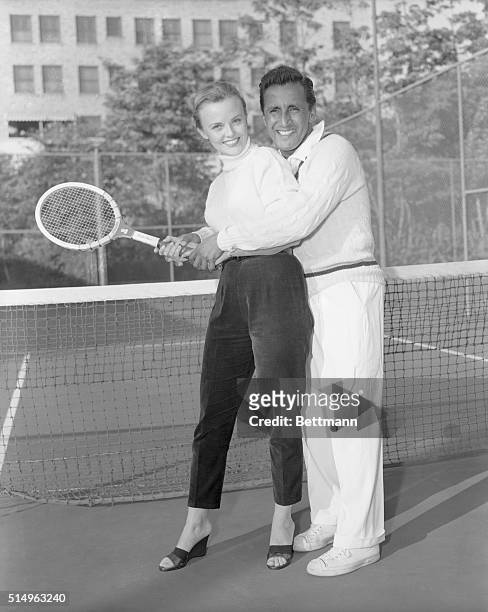 Pancho Segura gives lovely film and TV actress Ann Baker a practical demonstration of his famous two handed tennis grip. Ann has been chosen by the...