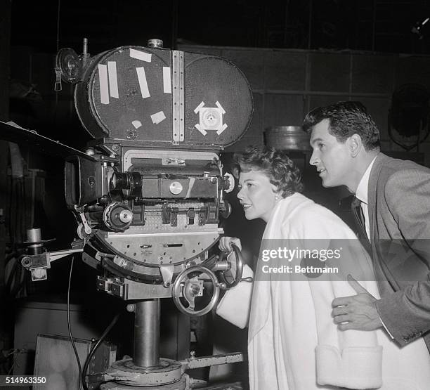 Film star Rock Hudson explains the movie camera to his new bride, the former Phyllis Gates, on the set of his new movie, Written on the Wind. They're...