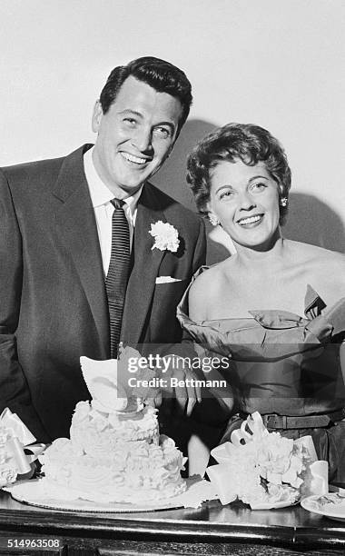 Actor Rock Hudson, 29. And his bride, Phyllis Gates smile happily as they prepare to cut their wedding cake at the Biltmore Hotel here following an...