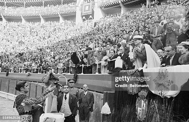 Princess Grace of Monaco tosses cap back to matador during a first class bullfight she and her bridegroom Prince Rainier III watched while stopping...