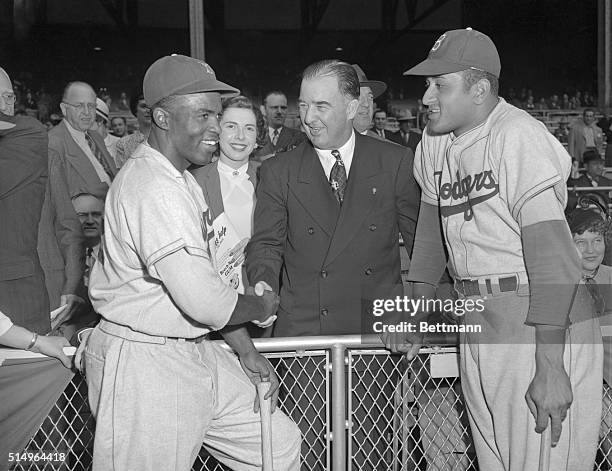 Baseball Commissioner A. B. Chandler, justifies his nickname, "Happy," as he poses with the two great Negro stars of the Brooklyn Dodgers, just...