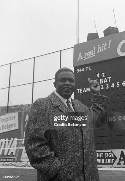 Brooklyn, NY: Fiery Dodger hero Jackie Robinson, who's finished with baseball, points to the Ebbets Field scoreboard, where the number 42, which he...