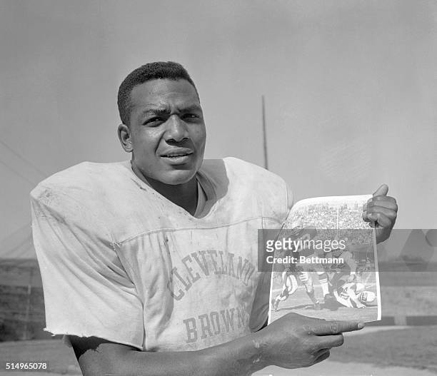 Jim Brown, Cleveland Browns' fullback, holds up a UPI photo of himself in action against the Chicago Cardinals October 12. Brown has picked up 482...