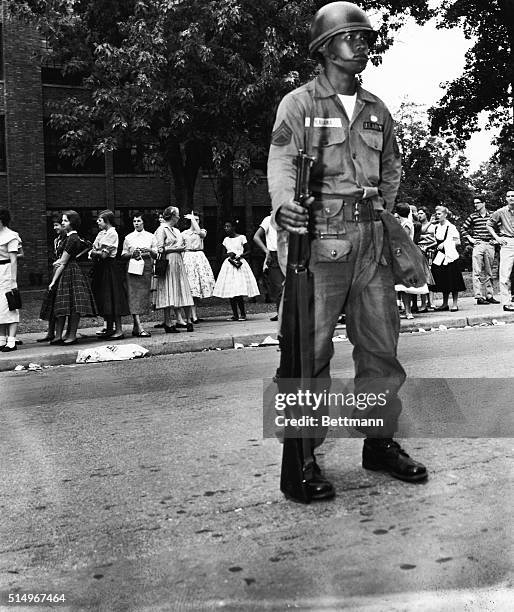 Paratrooper from the 101st Airborne division stands guard outside Little Rock's Central High school here on September 25th, as students chat during a...