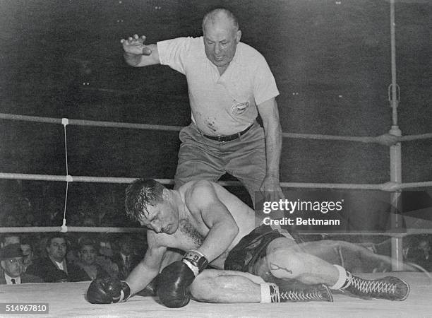 Canadian challenger Yvon Durelle lies dazed on the mat in the 11th round championship bout at Montreal Forum here, as referee Jack Sharkey begins the...